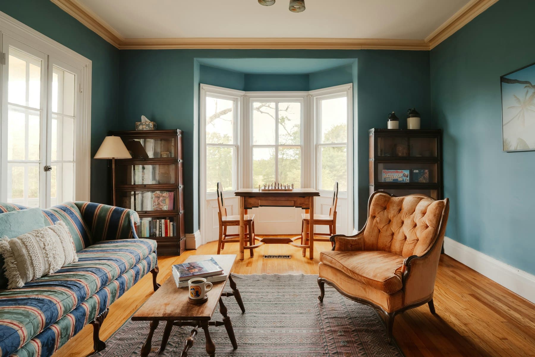Wohnzimmer in Petrol-Tönen mit gestreiftem Sofa und orangem Sessel
